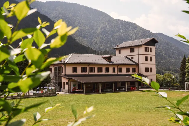 La casa vista dal prato, incorniciata dagli alberi